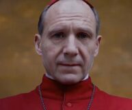 Ο Ralph Fiennes ντυμένος ως καρδινάλιος με κόκκινη στολή και καπέλο, από την ταινία Conclave.